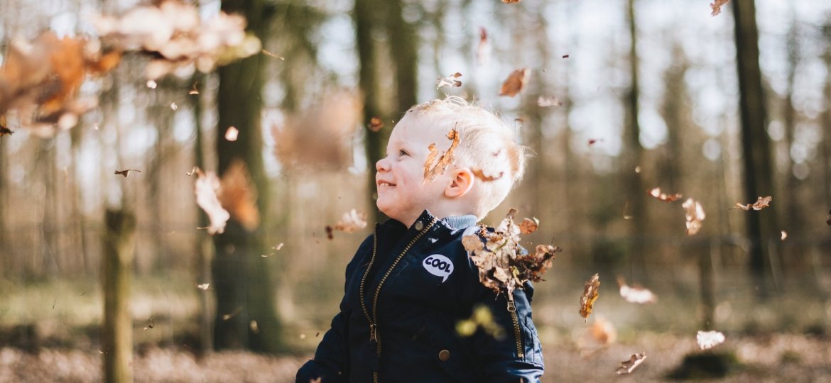 young boy laughing under falling leaves autumn perfectionism